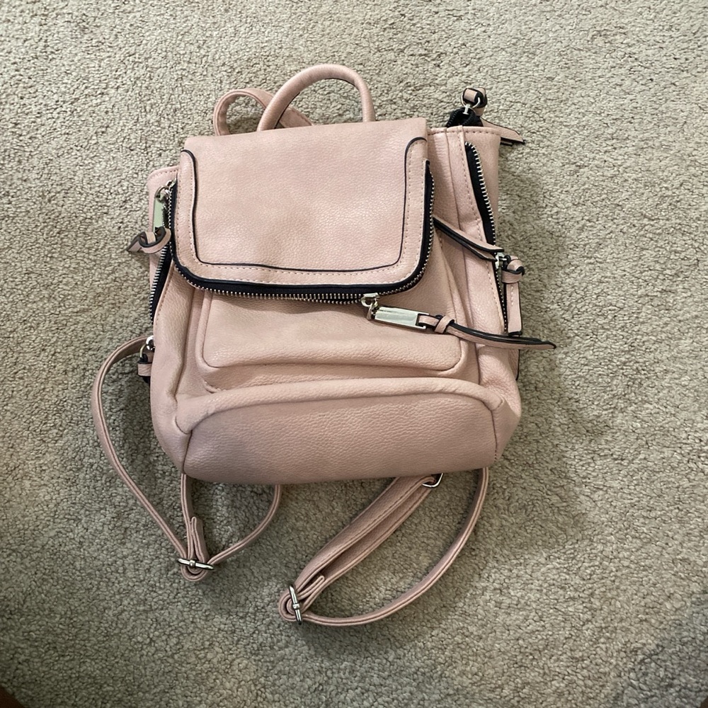 A pink purse/backpack that has been used and does have a hole in it